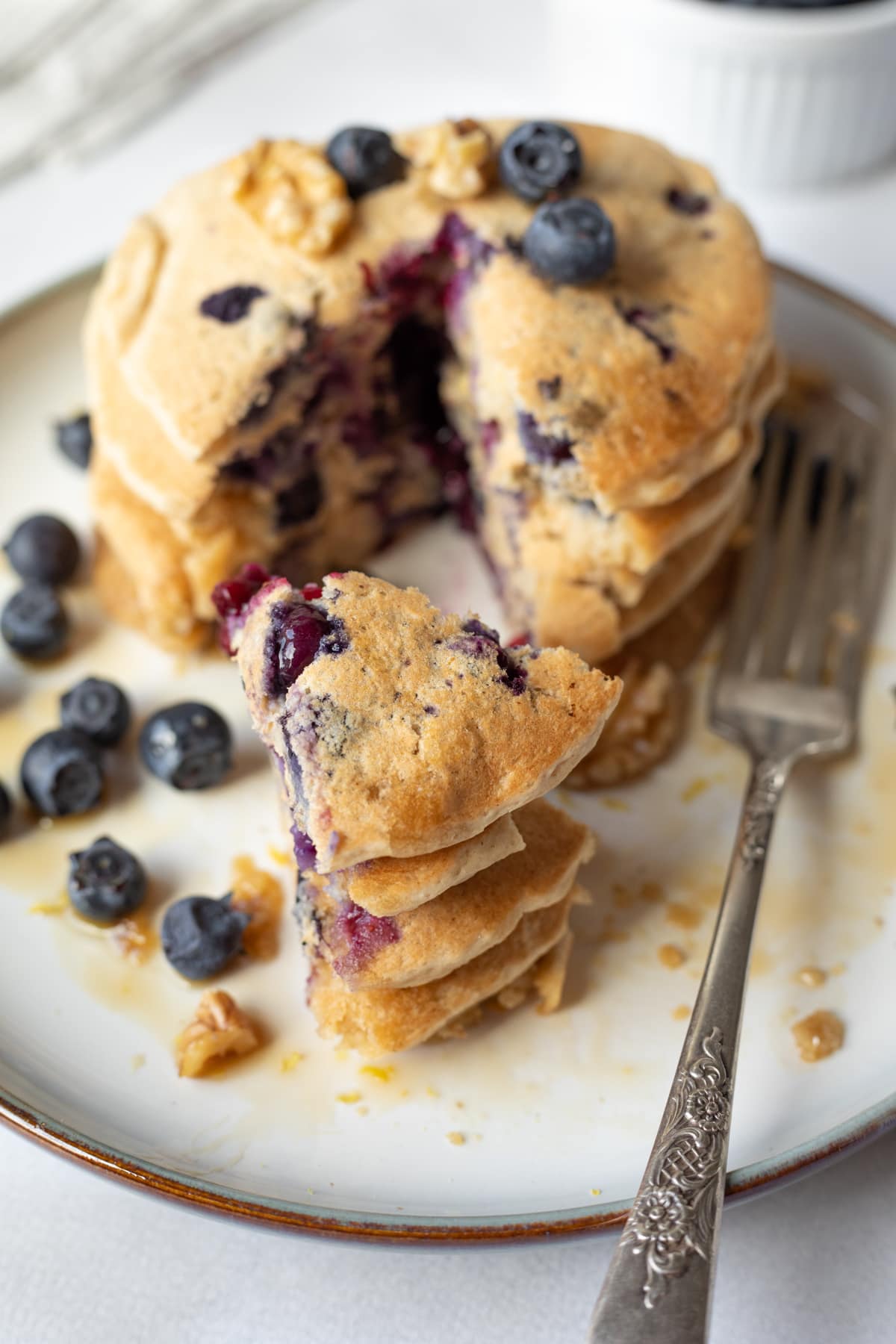 looking down at stack of golden pancakes with blueberries and syrup.