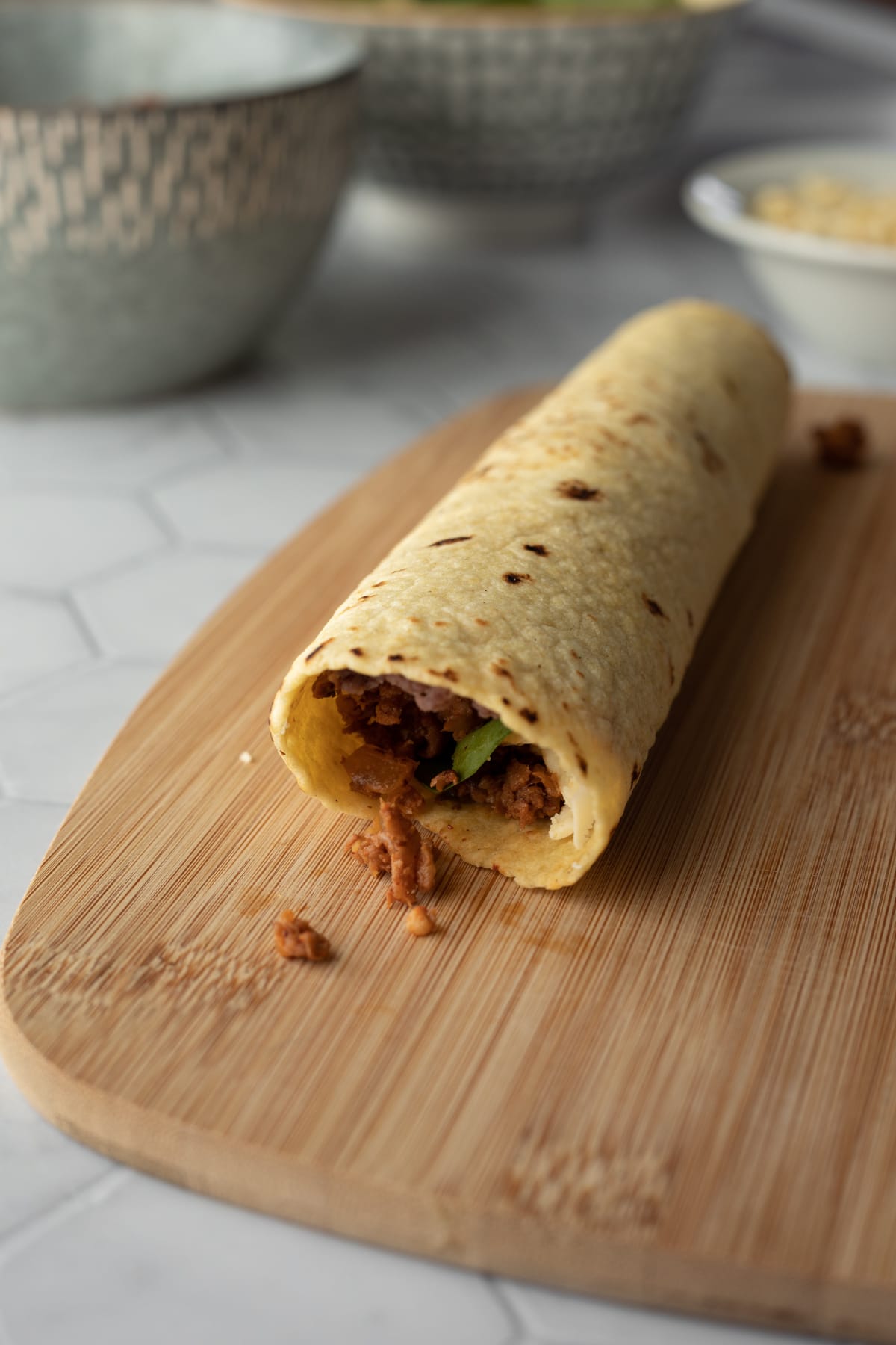 side view of tortilla stuffed, rolled up and ready to be baked.
