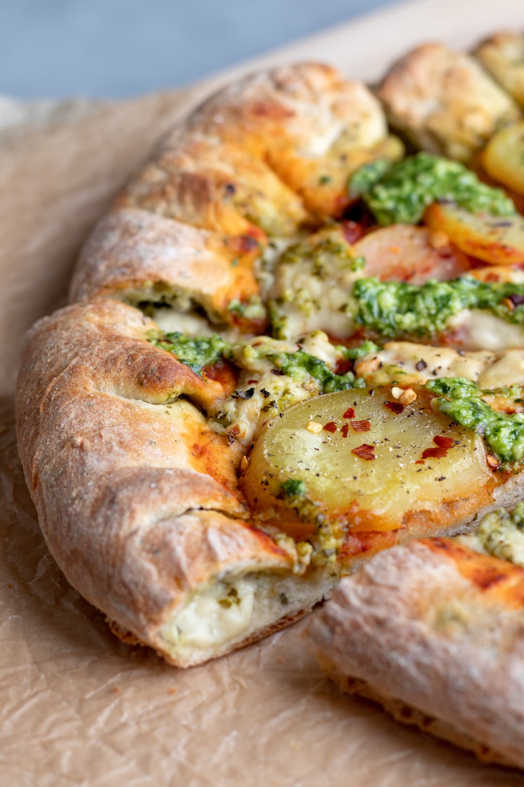 side view of vegan stuffed crust pizza  with pesto, cheese, and potato.