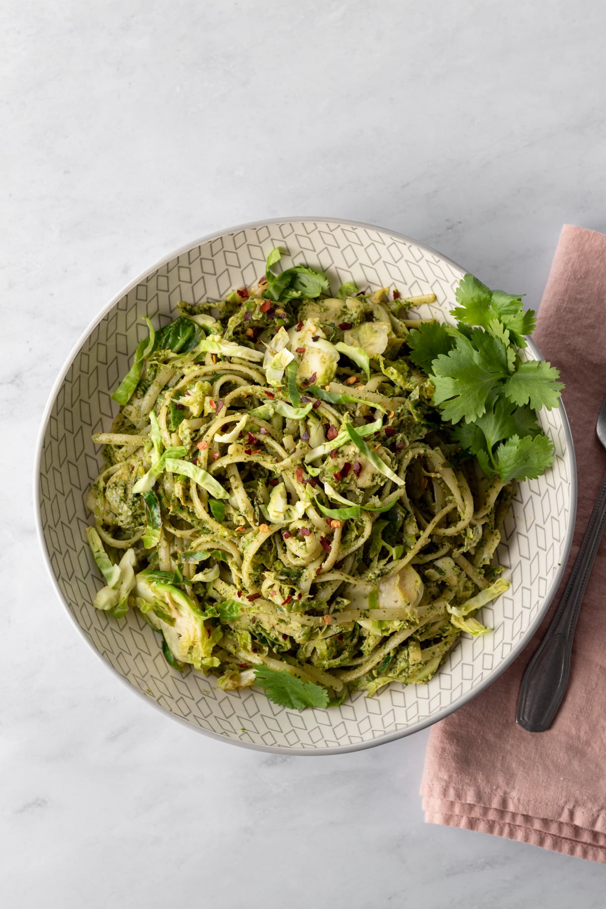 a bowl of pasta and brussels sprouts tossed with spicy cilantro sauce.