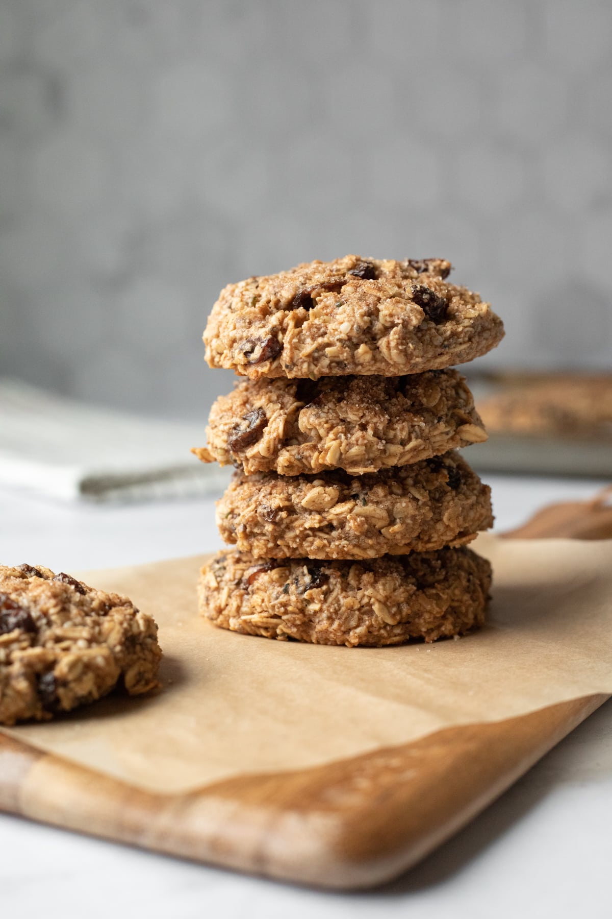 stack of 4 plump and chunky cookies agains a gray tile background.