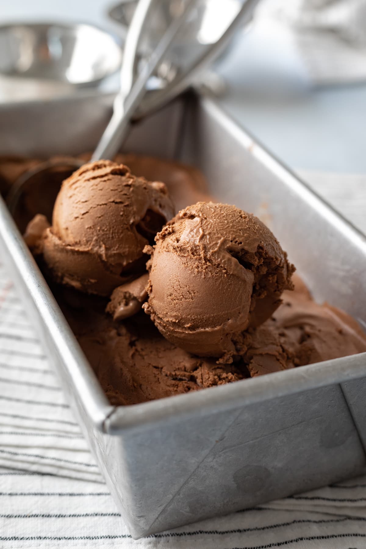 loaf pan filled with chocolate ice cream, 2 scoops on top.