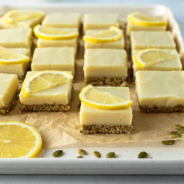 16 yellow lemon squares lined up on a pan