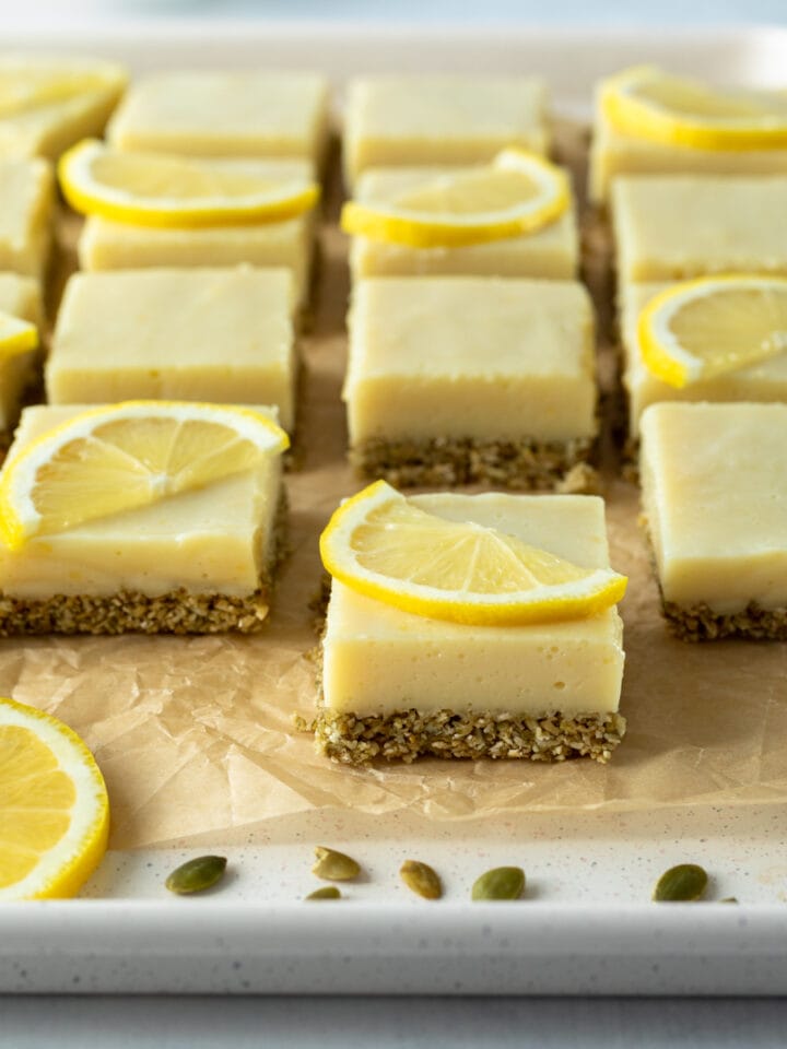 16 yellow lemon squares lined up on a pan