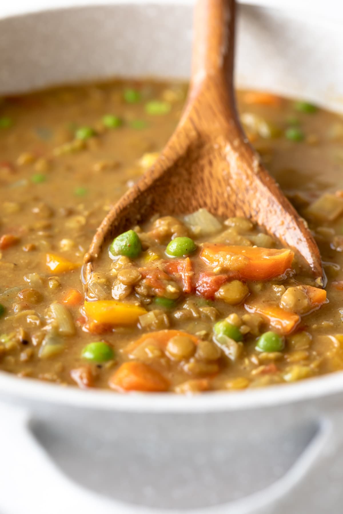 close up of creamy lentil soup scooped up by wood spoon