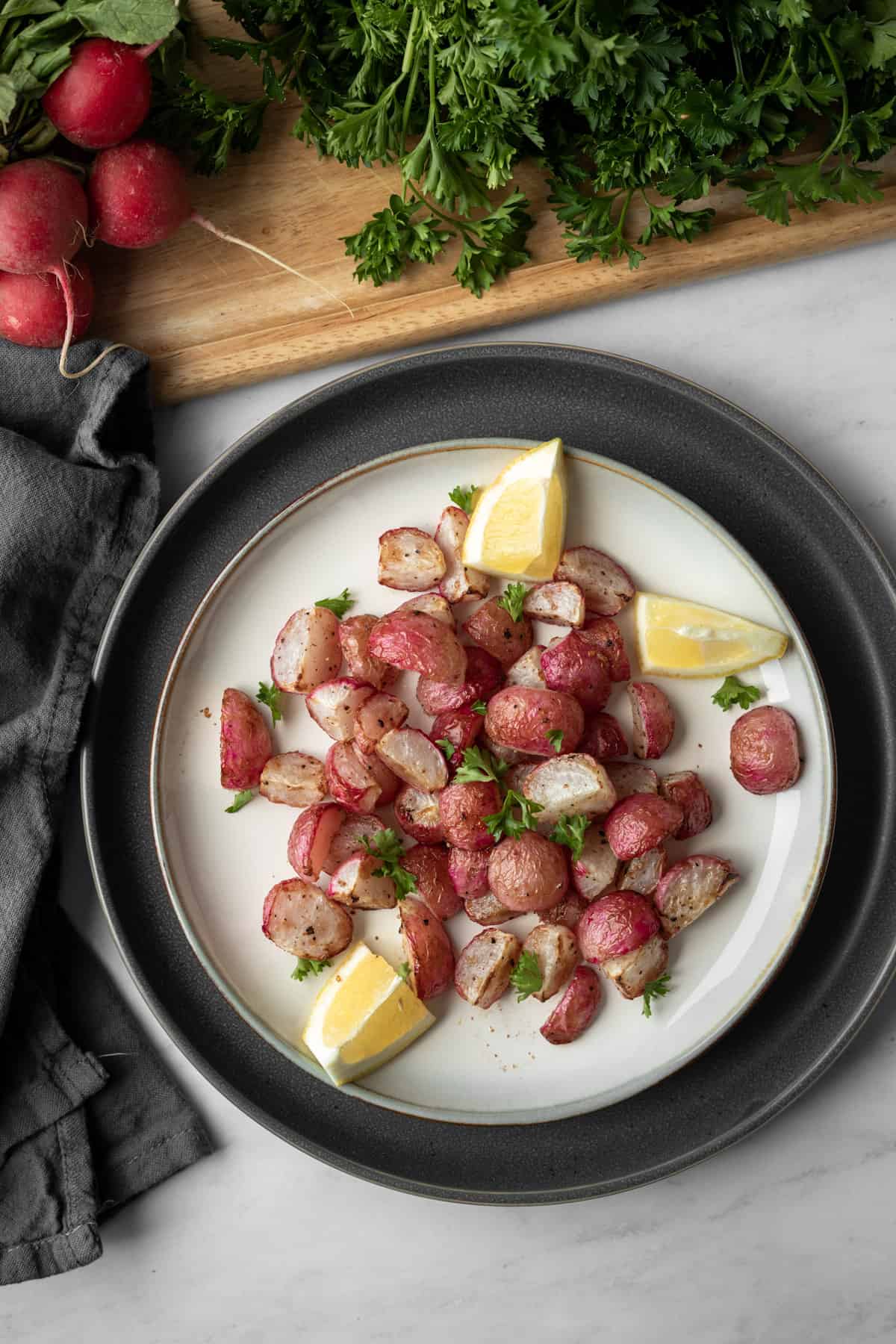 air fryer roasted radishes and lemon wedges on a white plate.