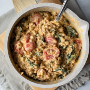 close up of creamy and cheesy farro mixed with kale and tomatoes in a small pot