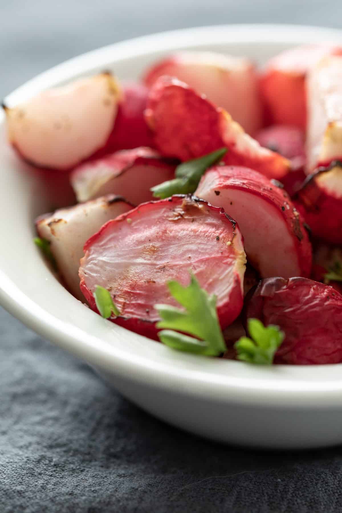 close up shot of oil-free air fried radishes garnished with chopped parsley.