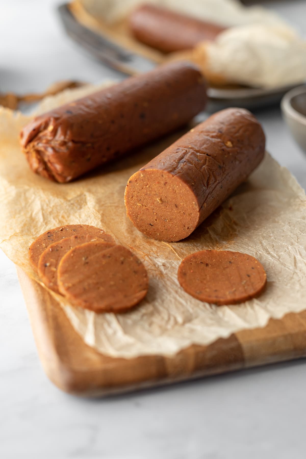 sliced log of vegan pepperoni on a cutting board showing the inside meaty texture.