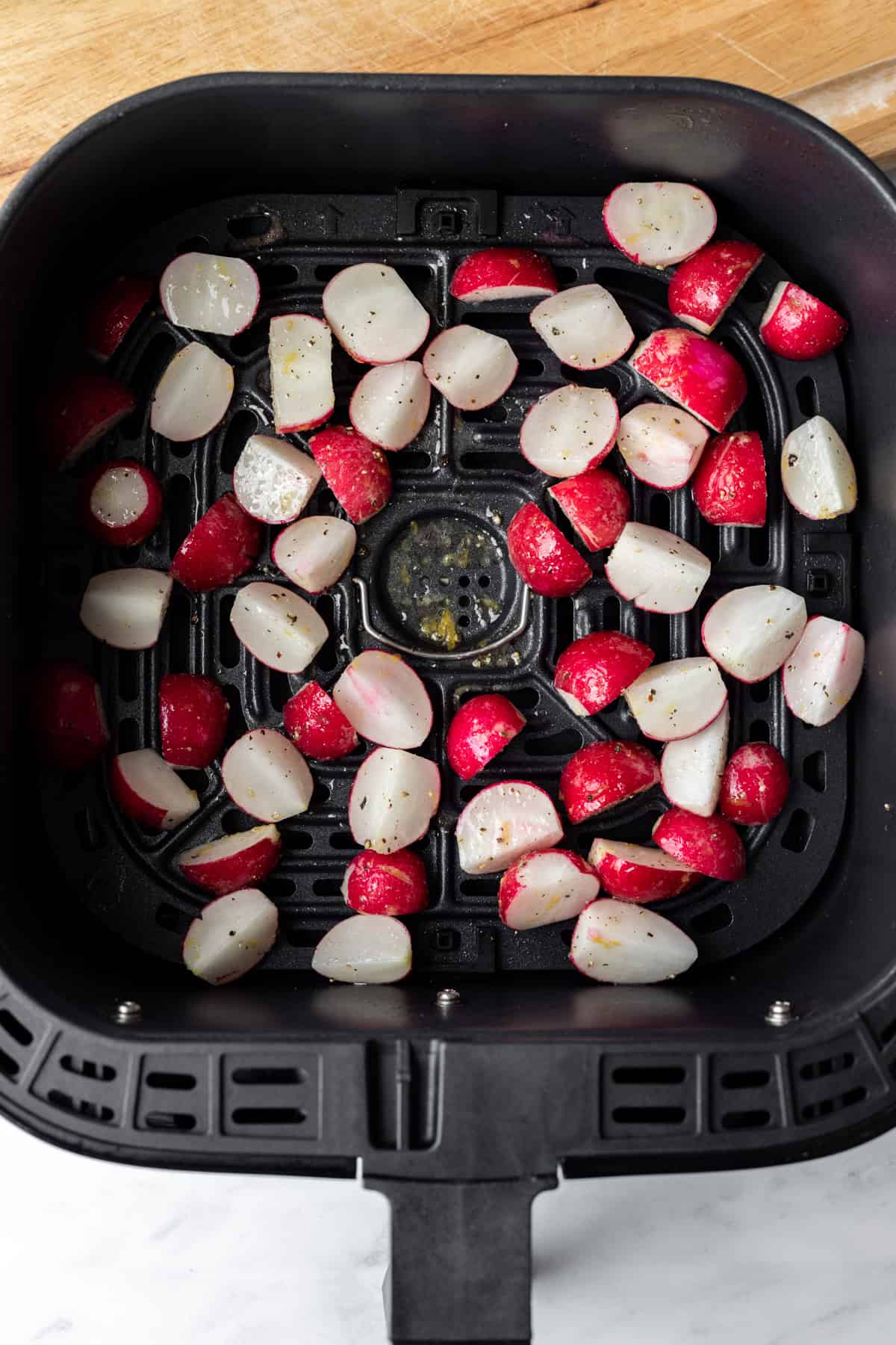 trimmed radishes inside an air fryer basket.