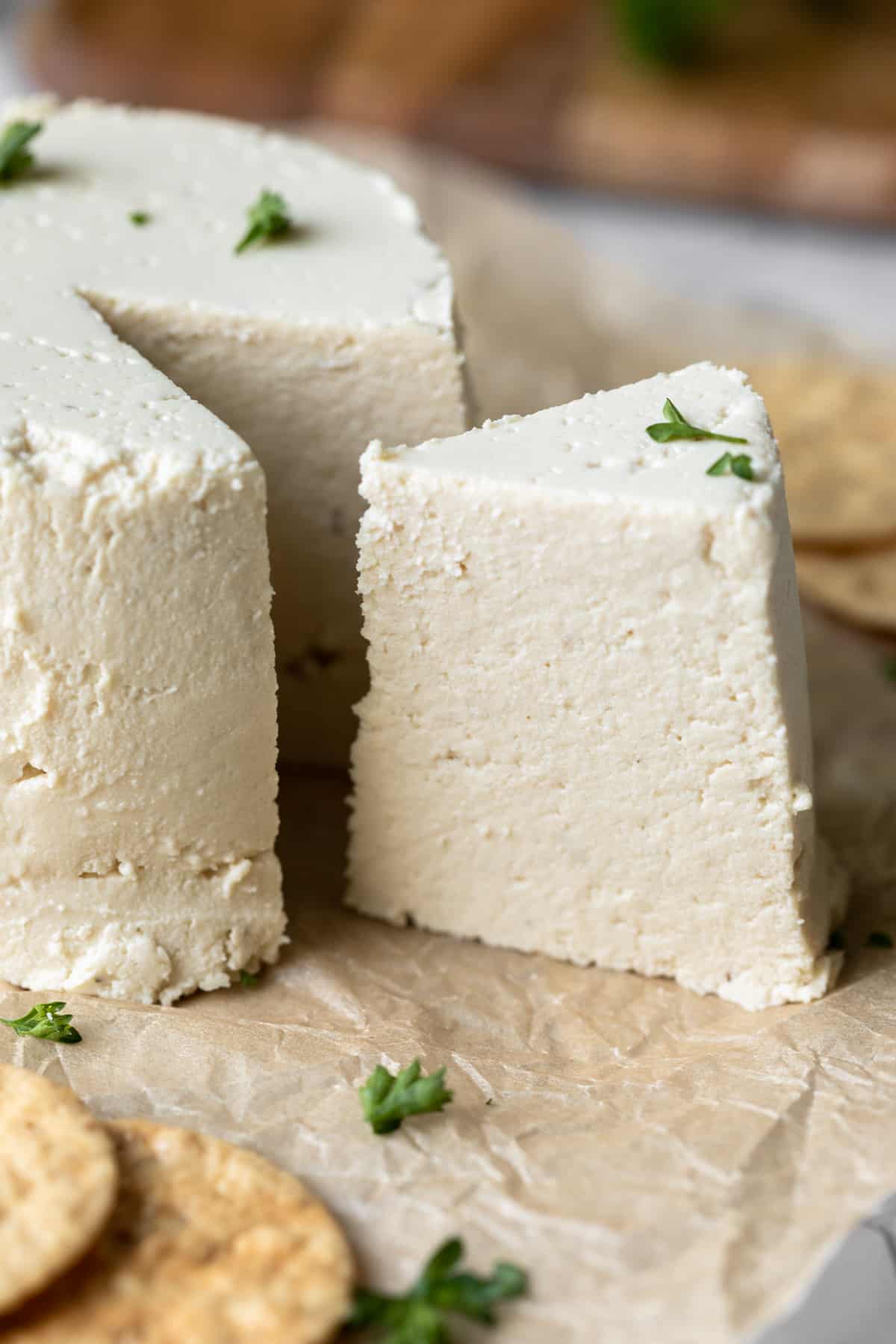 close up side view showing a wedge of vegan feta cut from the wheel.