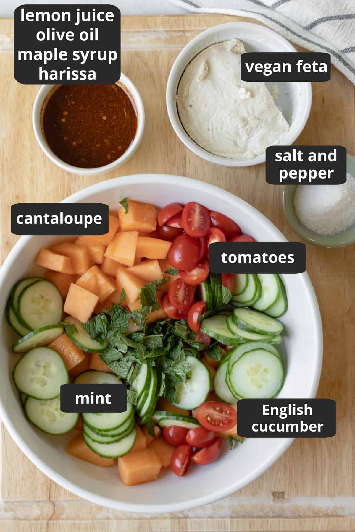 photo of ingredients with fruit and vegetables in a bowl, dressing and feta on the side.