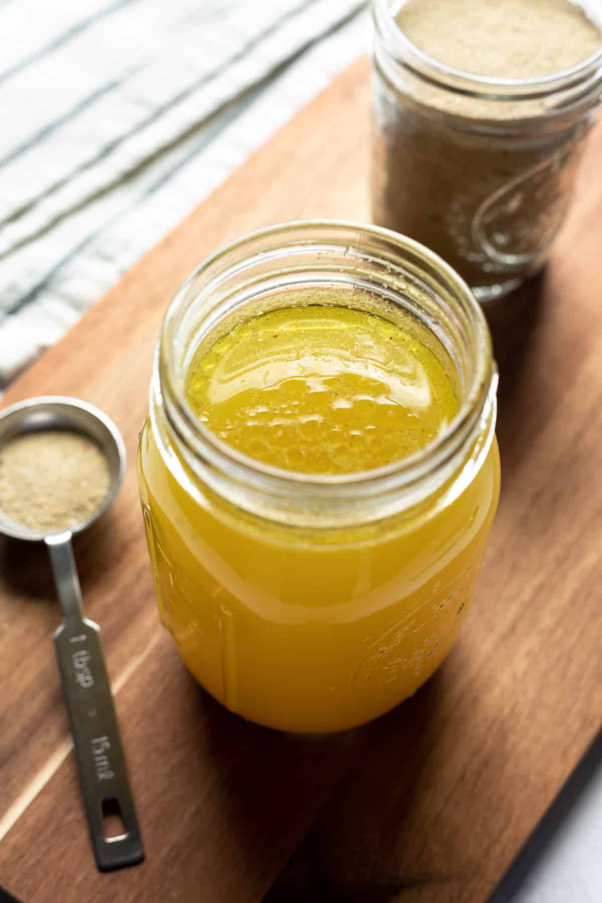 jar filled with golden vegan chicken broth with seasoning mix on the side.