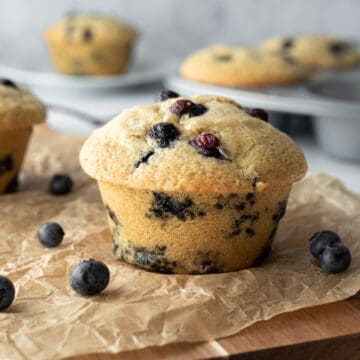 blueberry muffin on a board with more muffins in background.