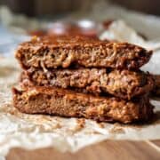 Three saucy seitan ribs stacked on a serving platter.