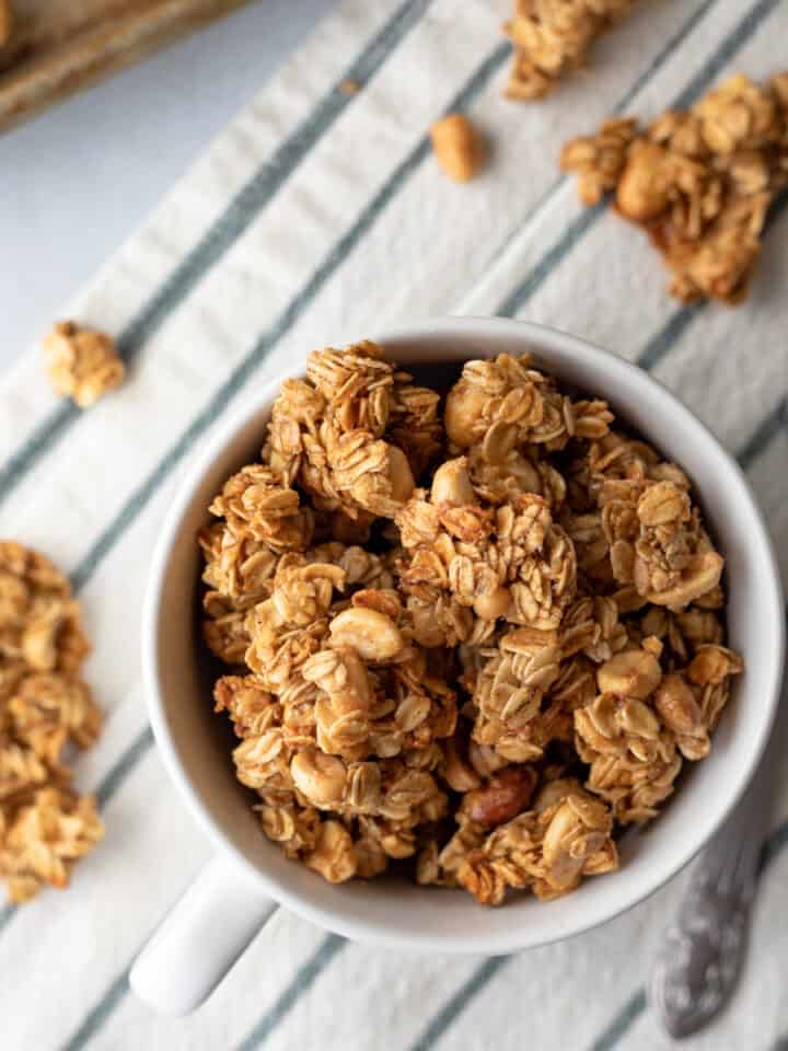 clusters of granola with peanuts in a mug and nearby.