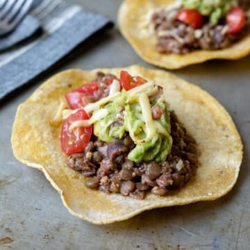 close up of lentil tacos dressed with guacamole and cheese.