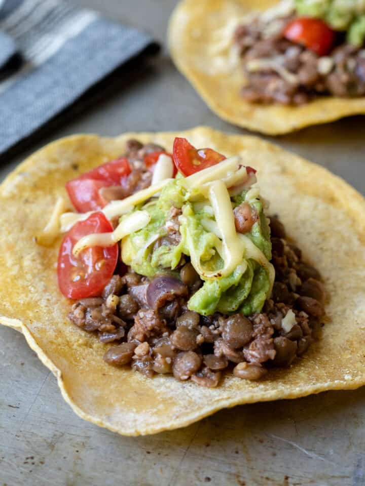close up of lentil tacos dressed with guacamole and cheese.