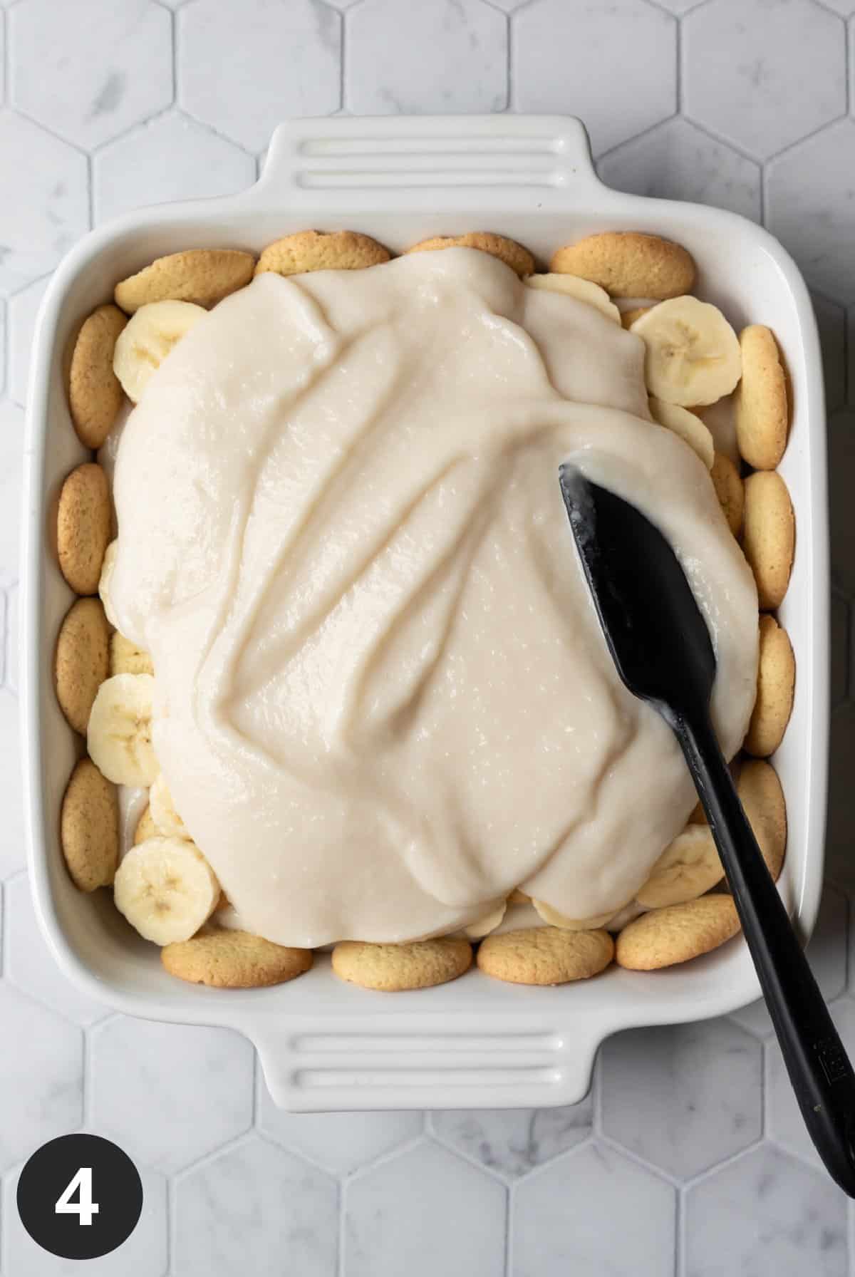 spreading the top layer of pudding over sliced bananas.