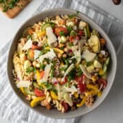 close up overhead view of vegan pasta salad topped with fresh herbs and dairy-free cheese.