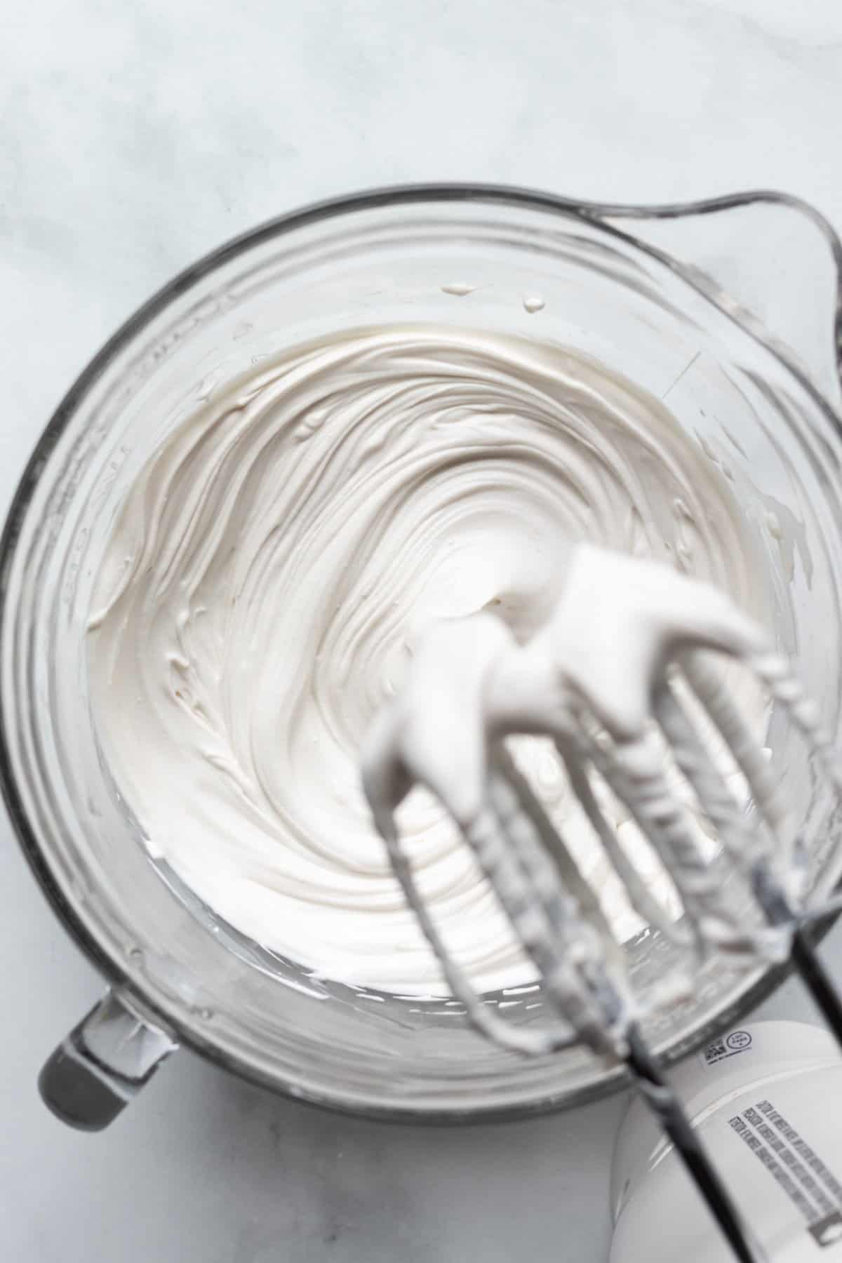 using handheld mixer to cream together cream cheese and sugar.