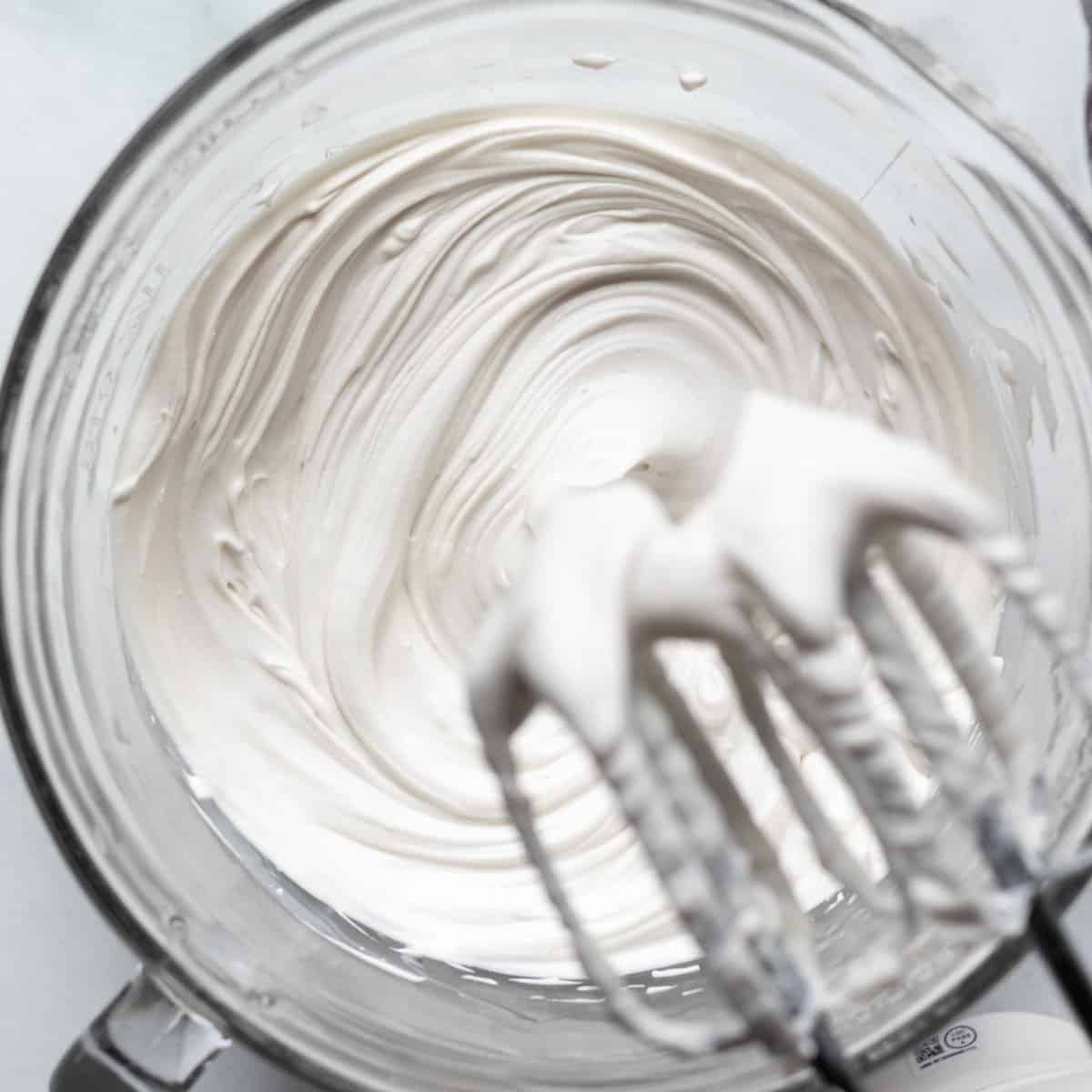 close up of beaters and whipped cream cheese in a bowl.