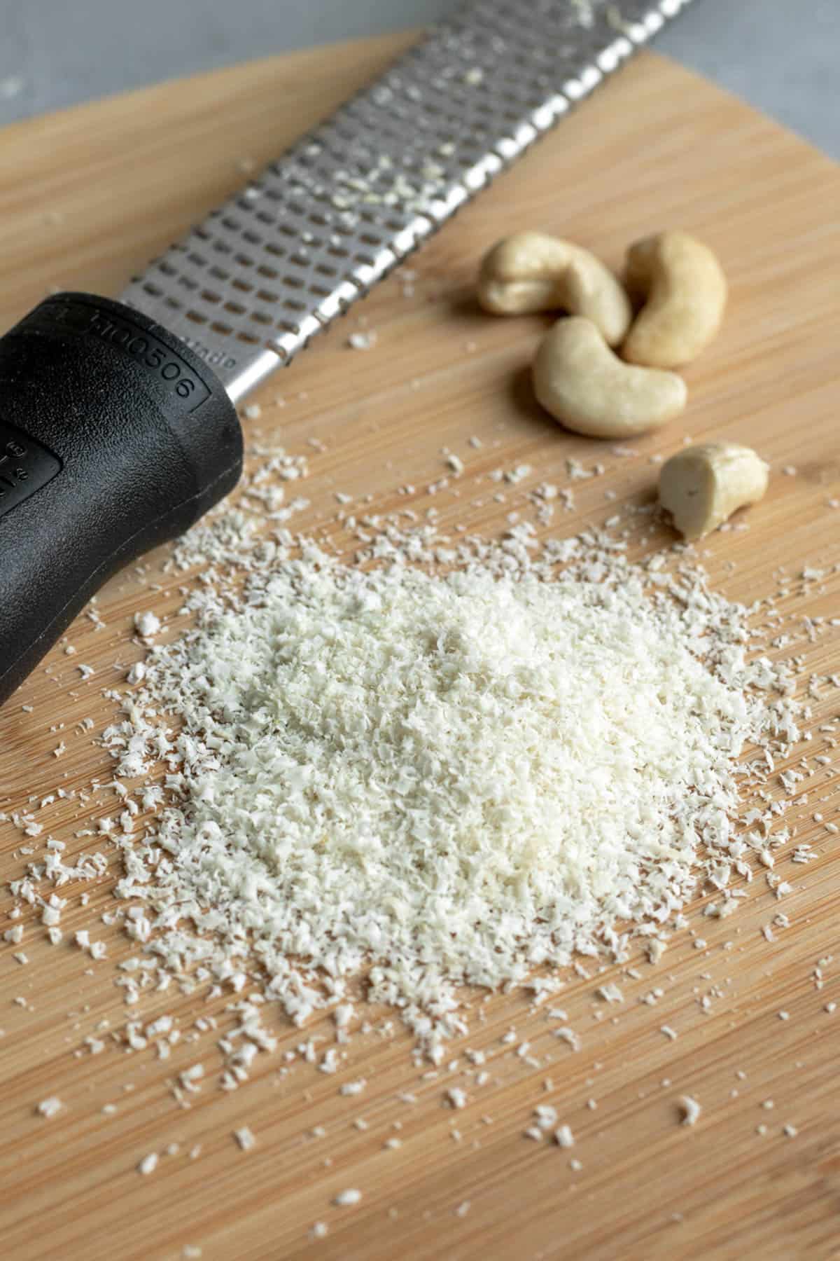 zesting cashews on a microplane for a vegan Parmesan substitute.