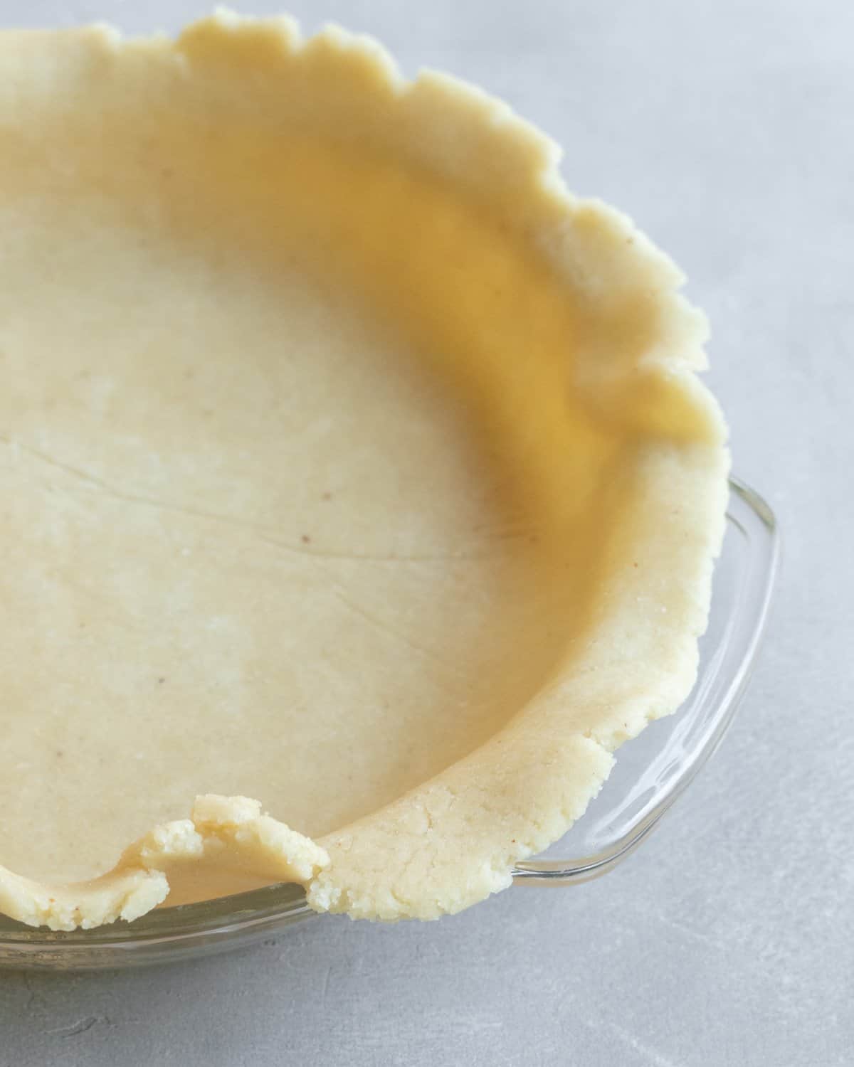 close up of unbaked pie crust in a glass pie plate.