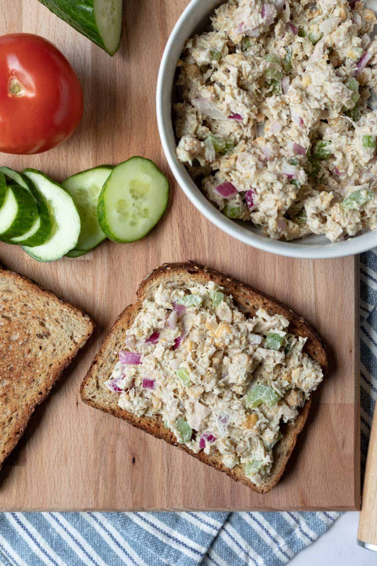 overhead view of assembling a chickpea chicken salad sandwich on a cutting board.