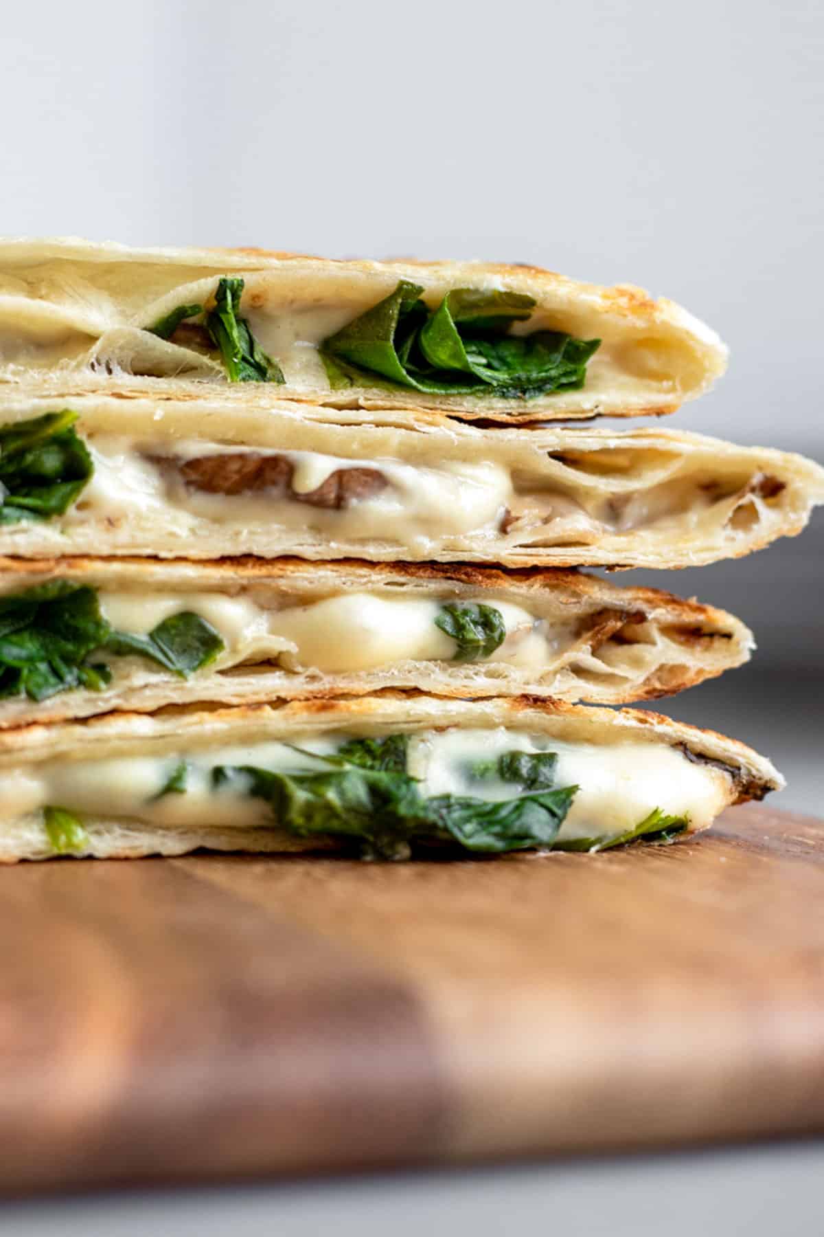 close up view of crisp vegan quesadilla stacked on a cutting board.