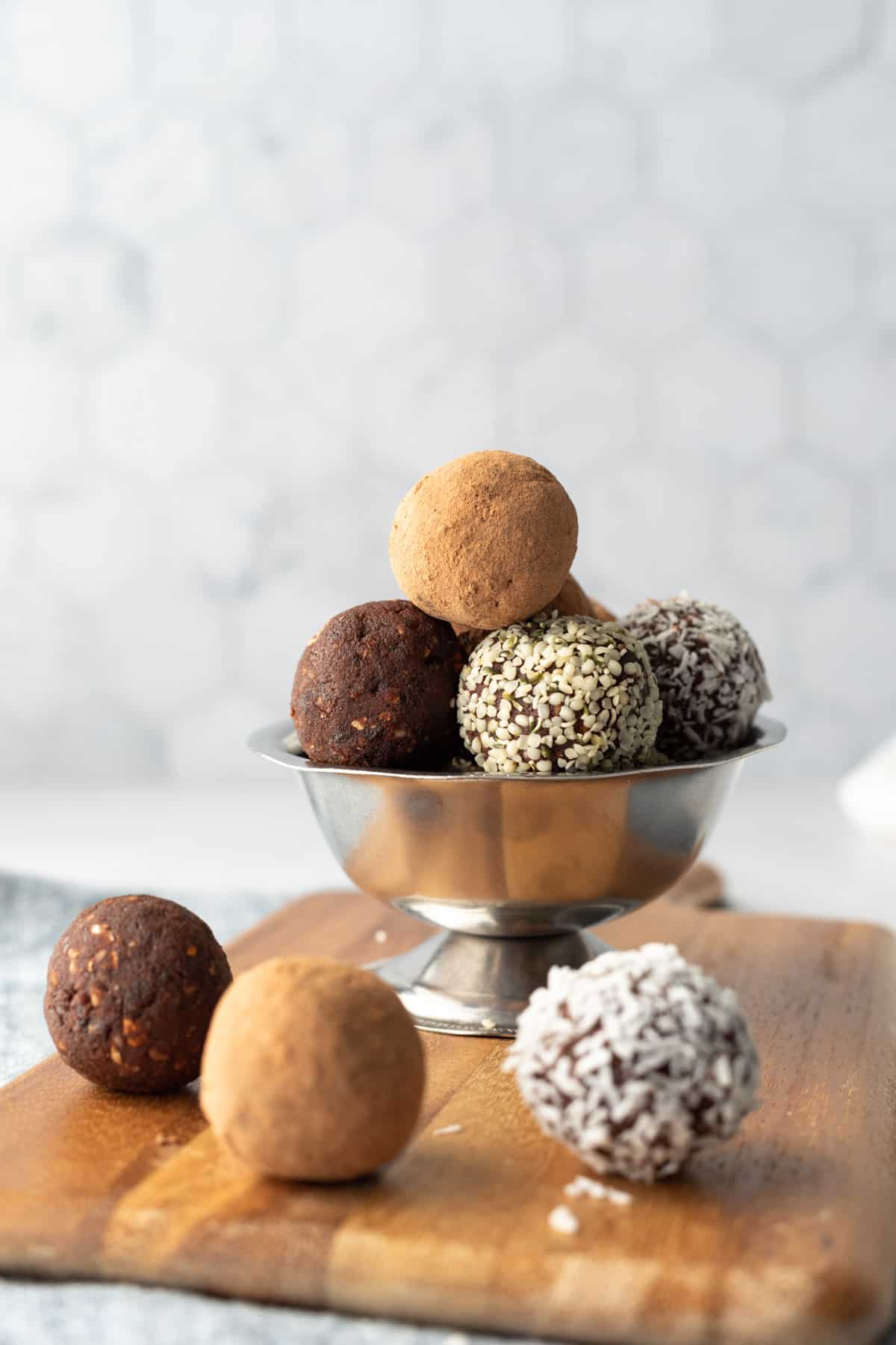 Grain-free energy balls in a small bowl, rolled in cacao, hemp seeds, or coconut. 