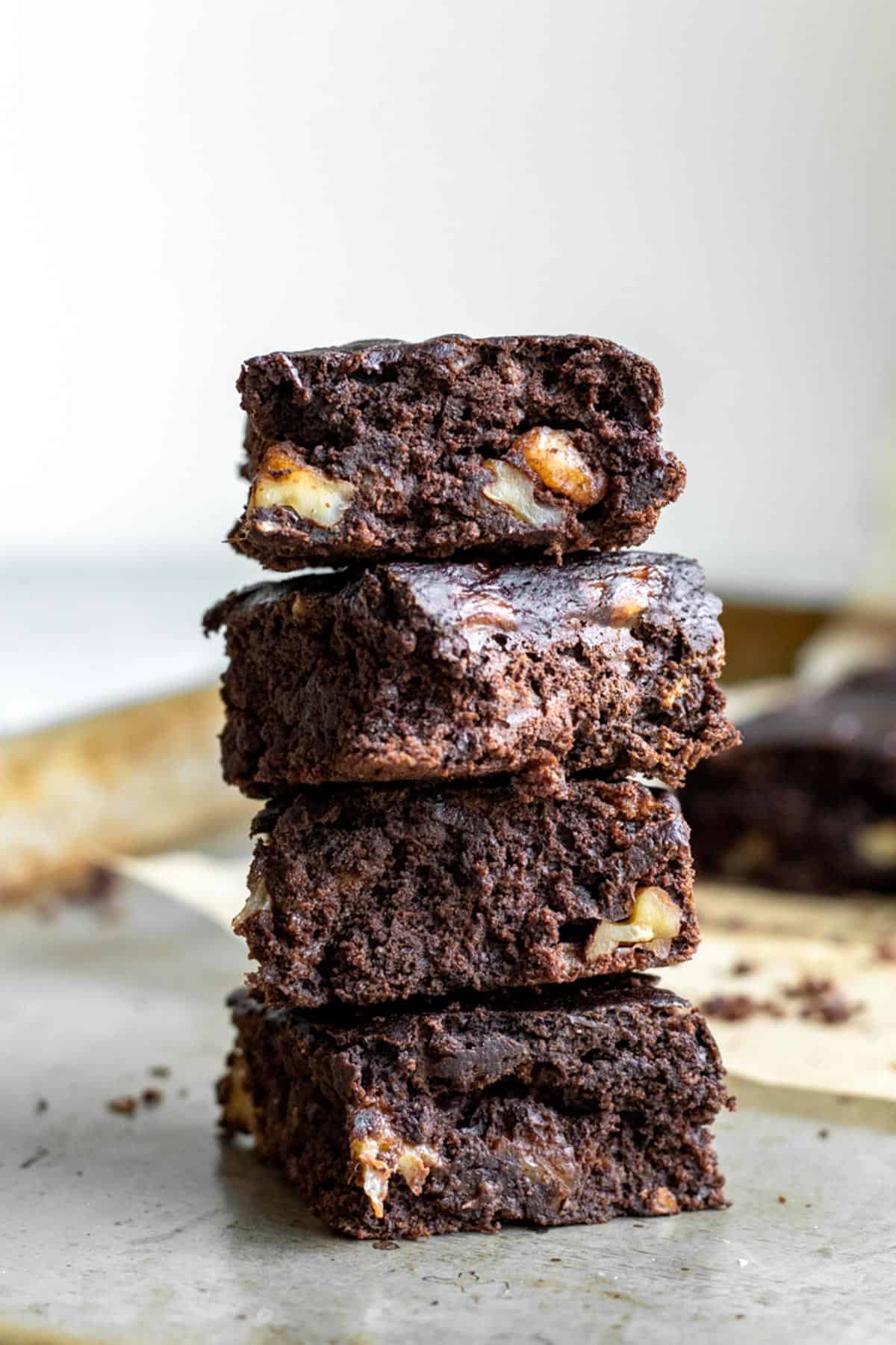a stack of healthy brownies showing texture and walnuts inside.