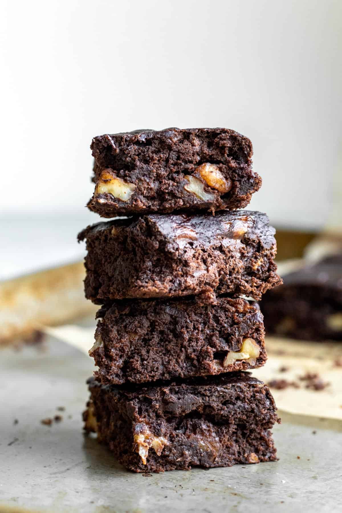 A stack of 4 vegan banana brownies with walnuts.