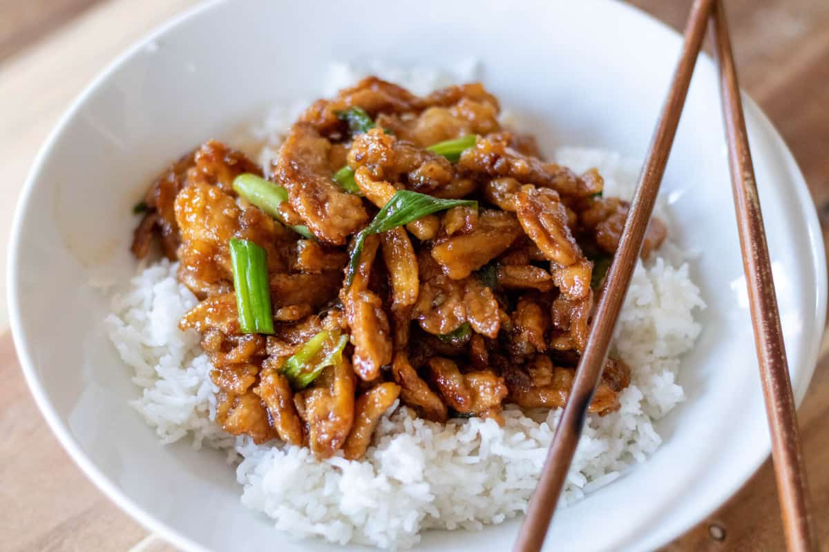 Mongolian soy curls atop white rice in a white bowl.
