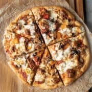 overhead view of a decadent homemade pizza with melted vegan cheese on top.
