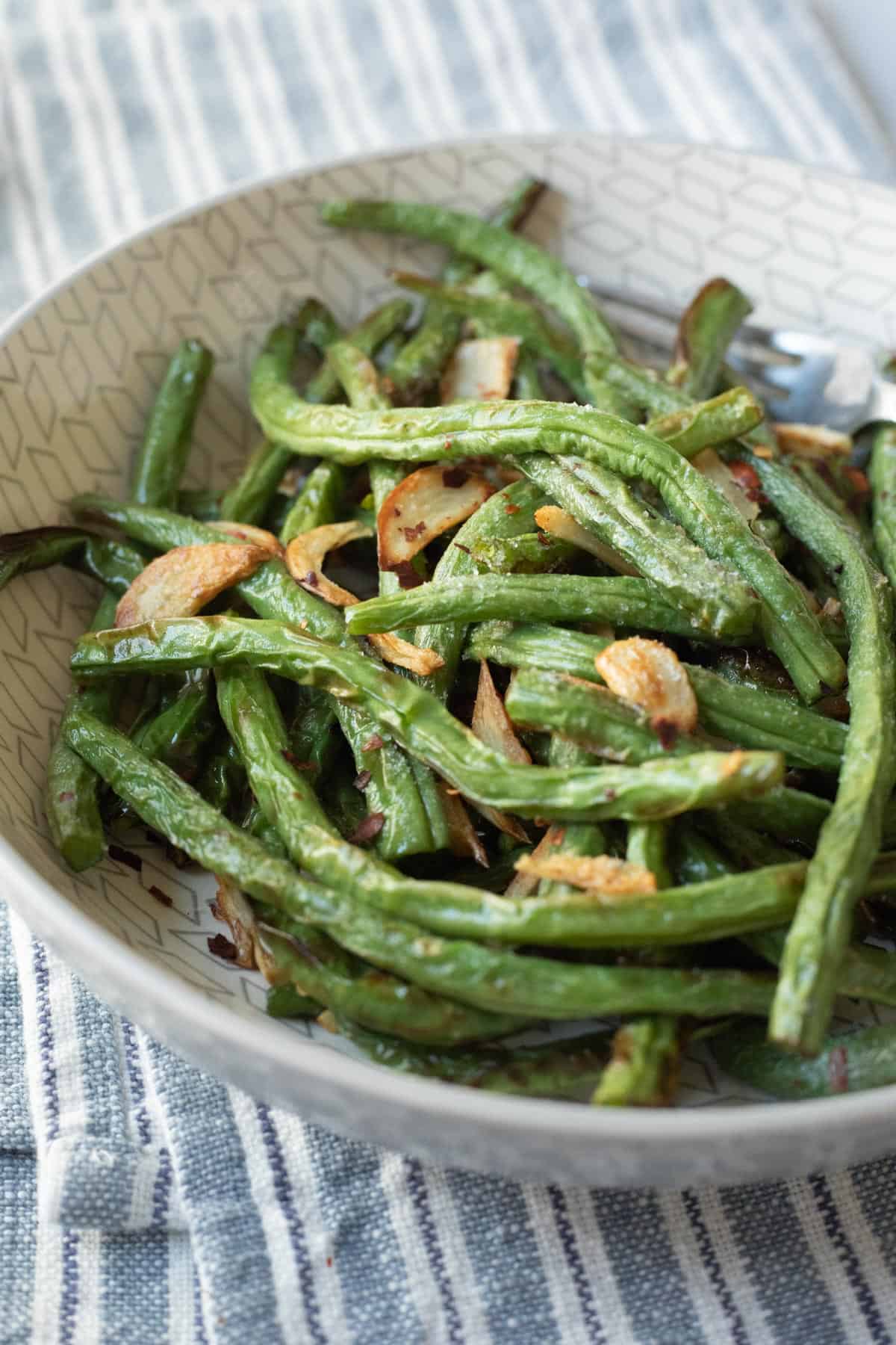 side view of garlicky air fryer green beans in a serving bowl.