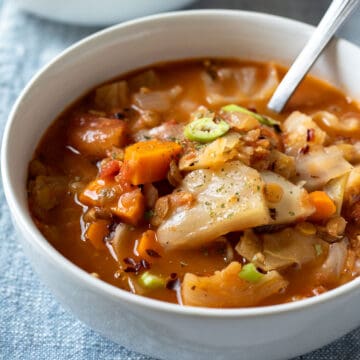 brightly lit photo of colorful cabbage soup in a white bowl.