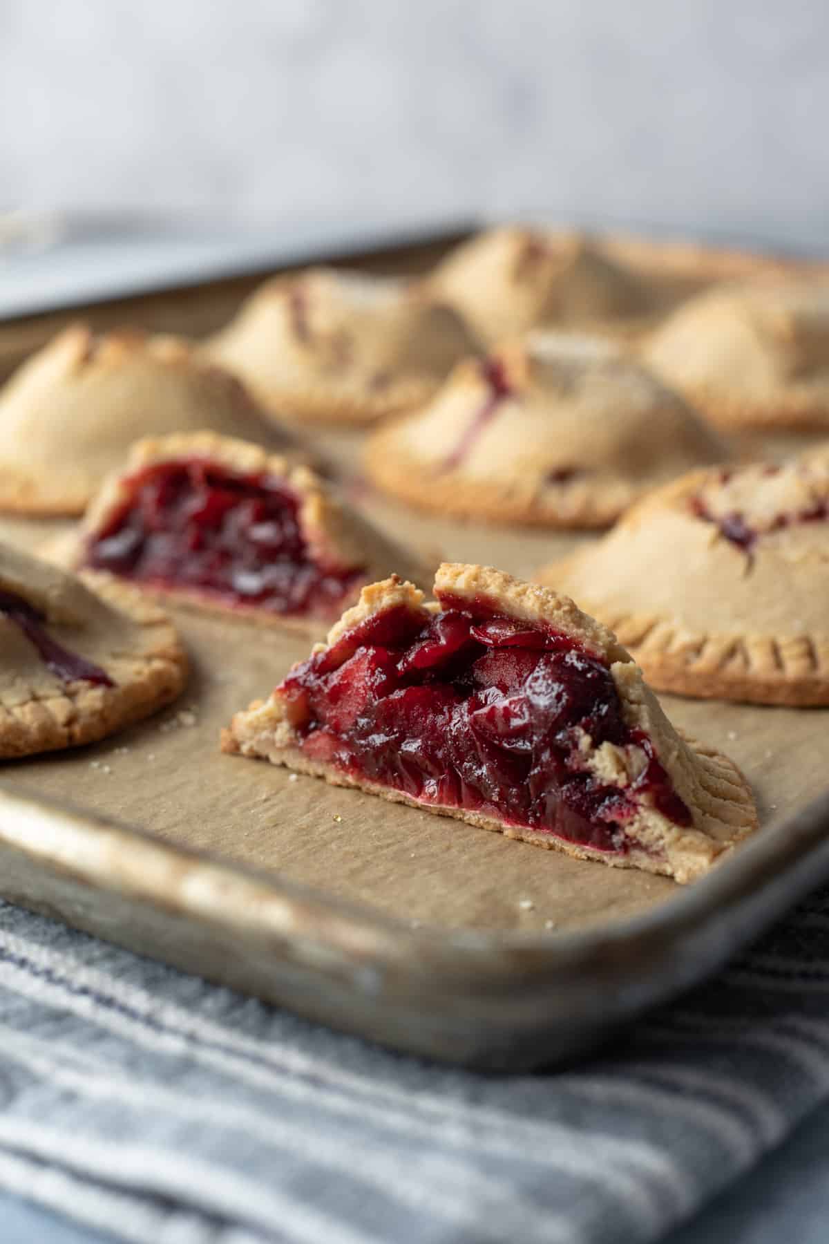 close up showing jammy red apple-cranberry filling inside vegan hand pies.
