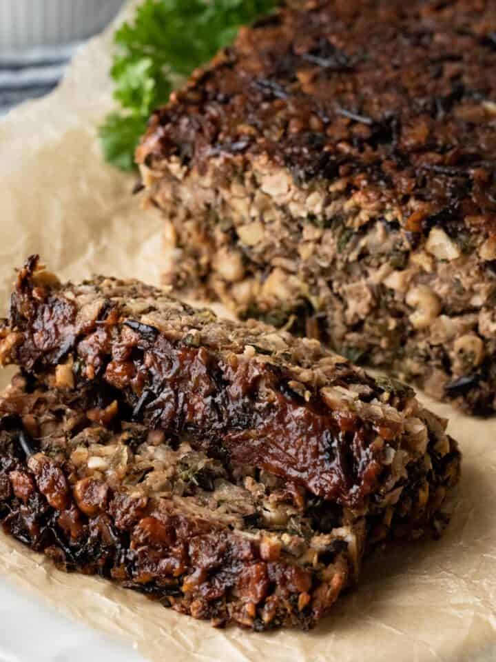 two slices of chickpea meatloaf with glaze resting on parchment paper.