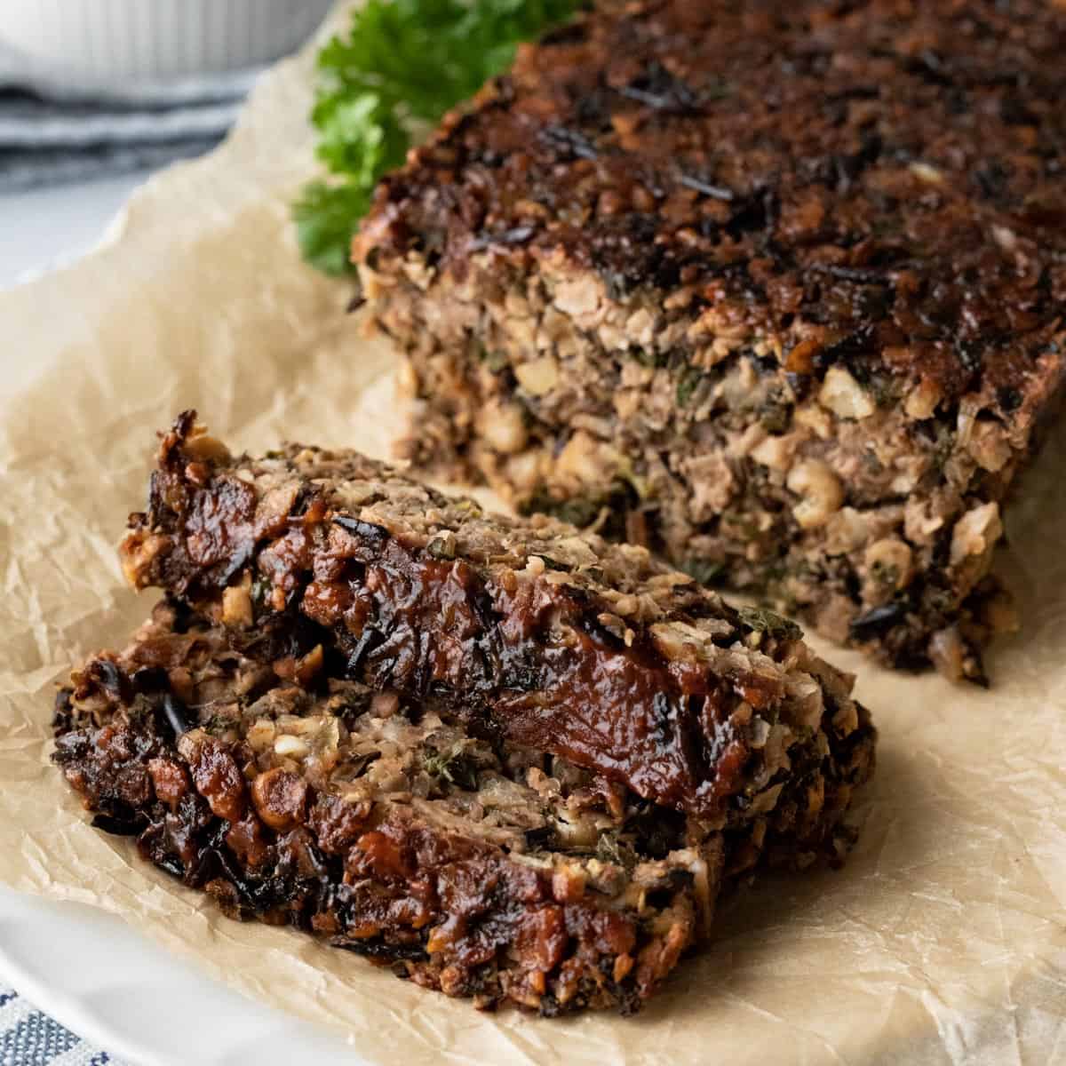 two slices of chickpea meatloaf with glaze resting on parchment paper.