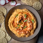 flavored hummus in a bowl surrounded by crackers.