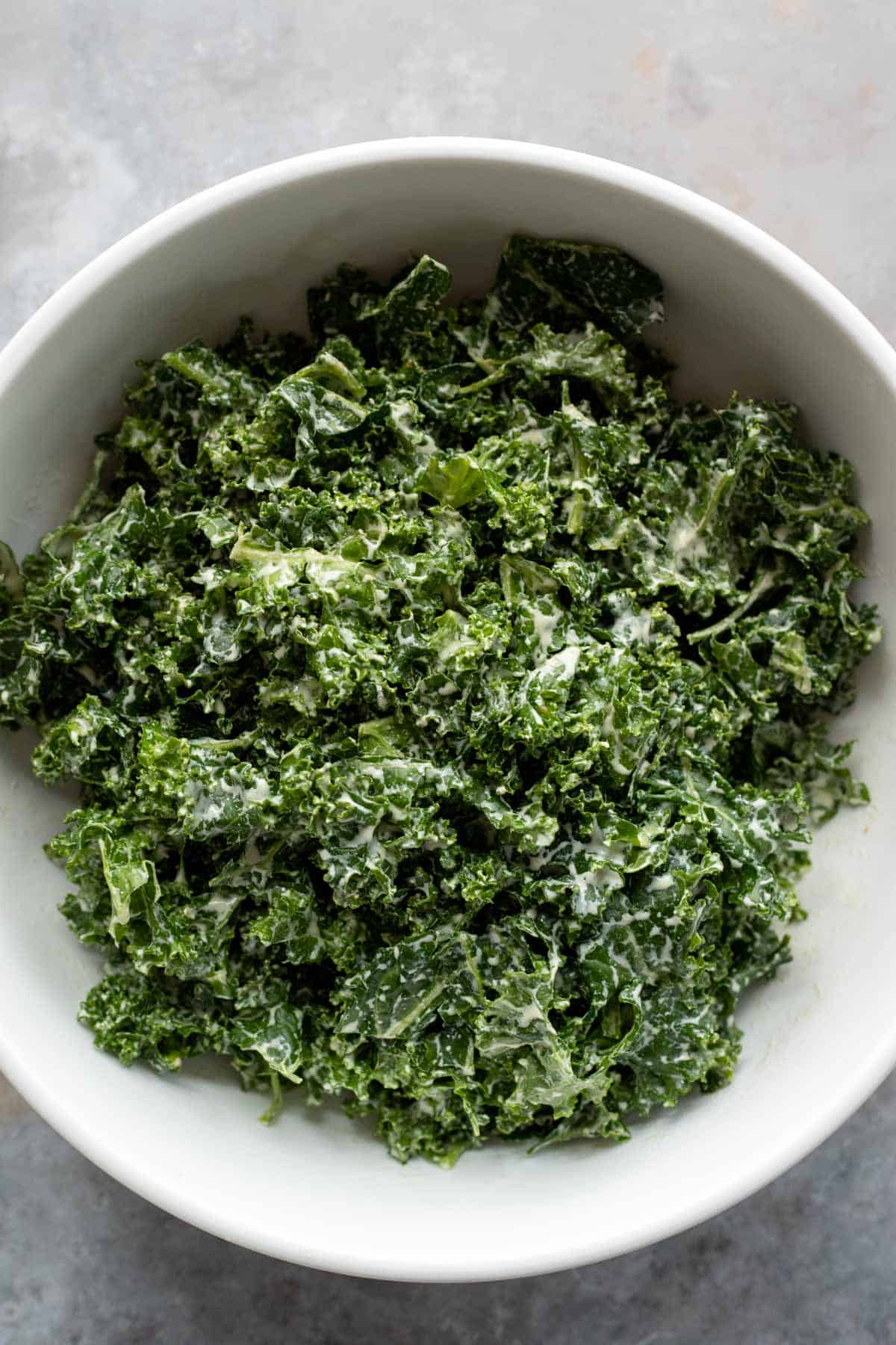 massaged kale in a bowl covered with creamy dressing.