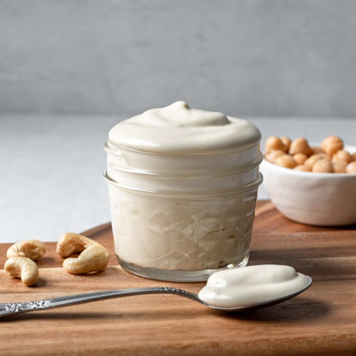 oil-free vegan mayo in a small glass jar resting on a wood cutting board.