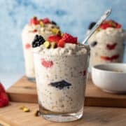 three glasses filled with creamy overnight oats topped with berries.