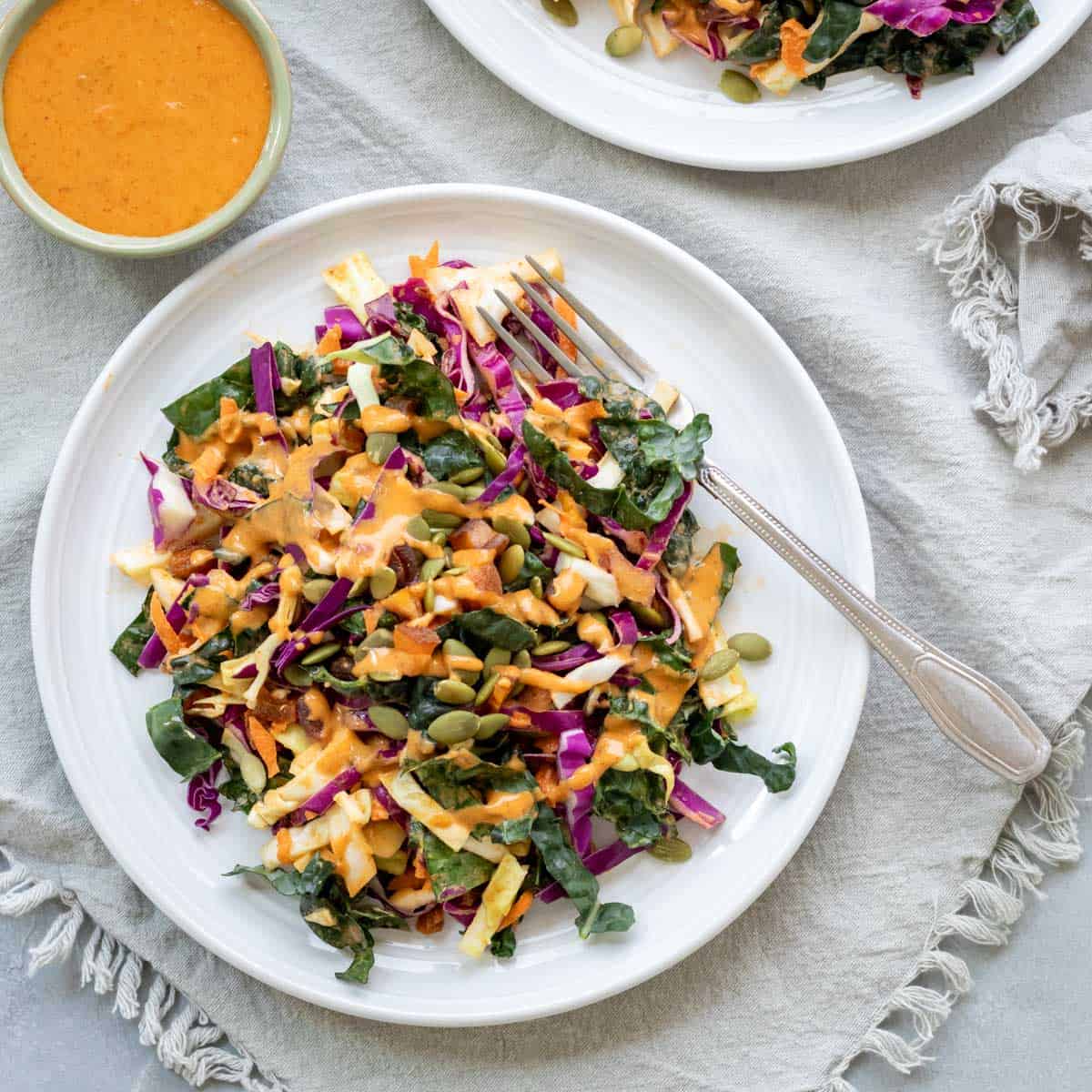 bright orange harissa dressing on a kale salad.