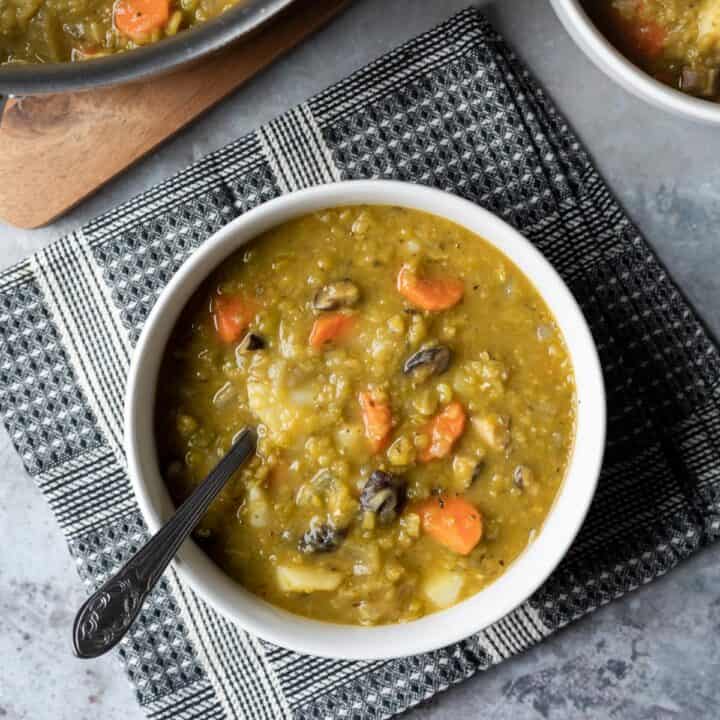 overhead photo of split pea soup with potatoes, carrots, and dried mushrooms in a bowl.