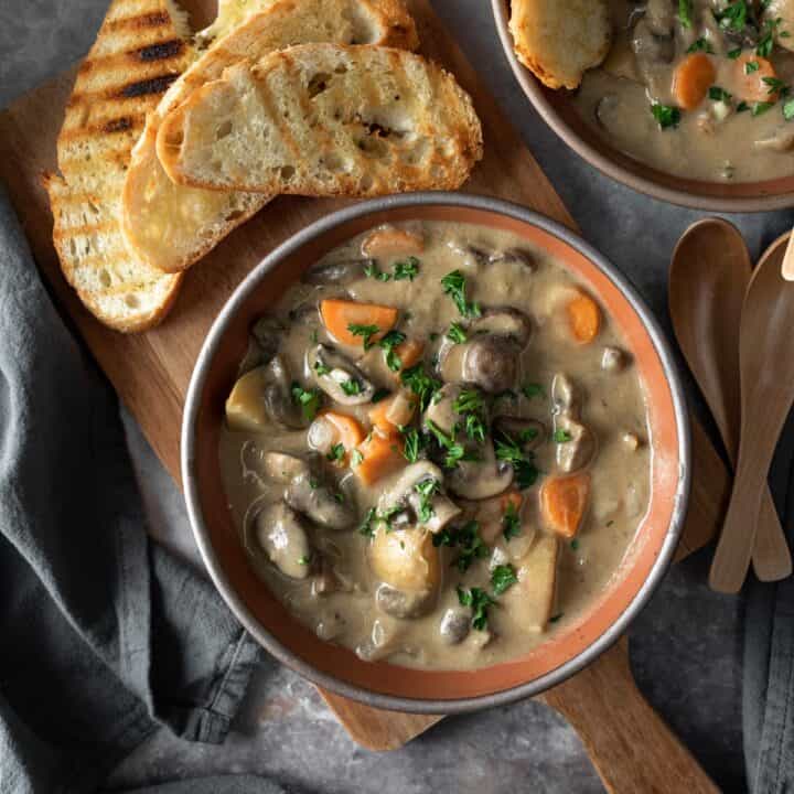 two bowls filled with creamy mushroom stew garnished with parsley.