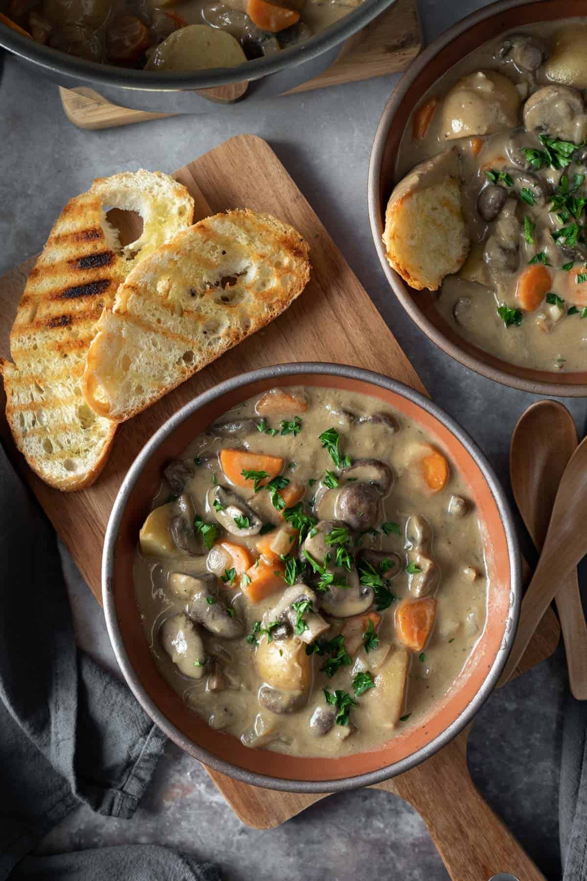 overhead photo of two bowls of mushroom stew served with toasted bread.