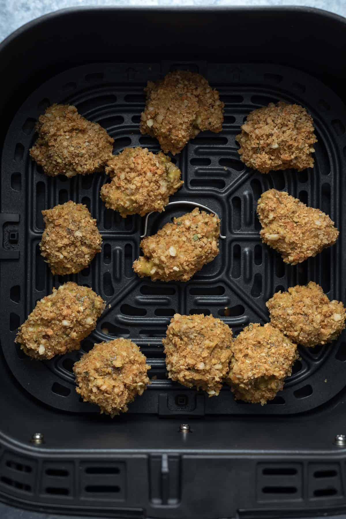 breaded seitan chicken in an air fryer basket.