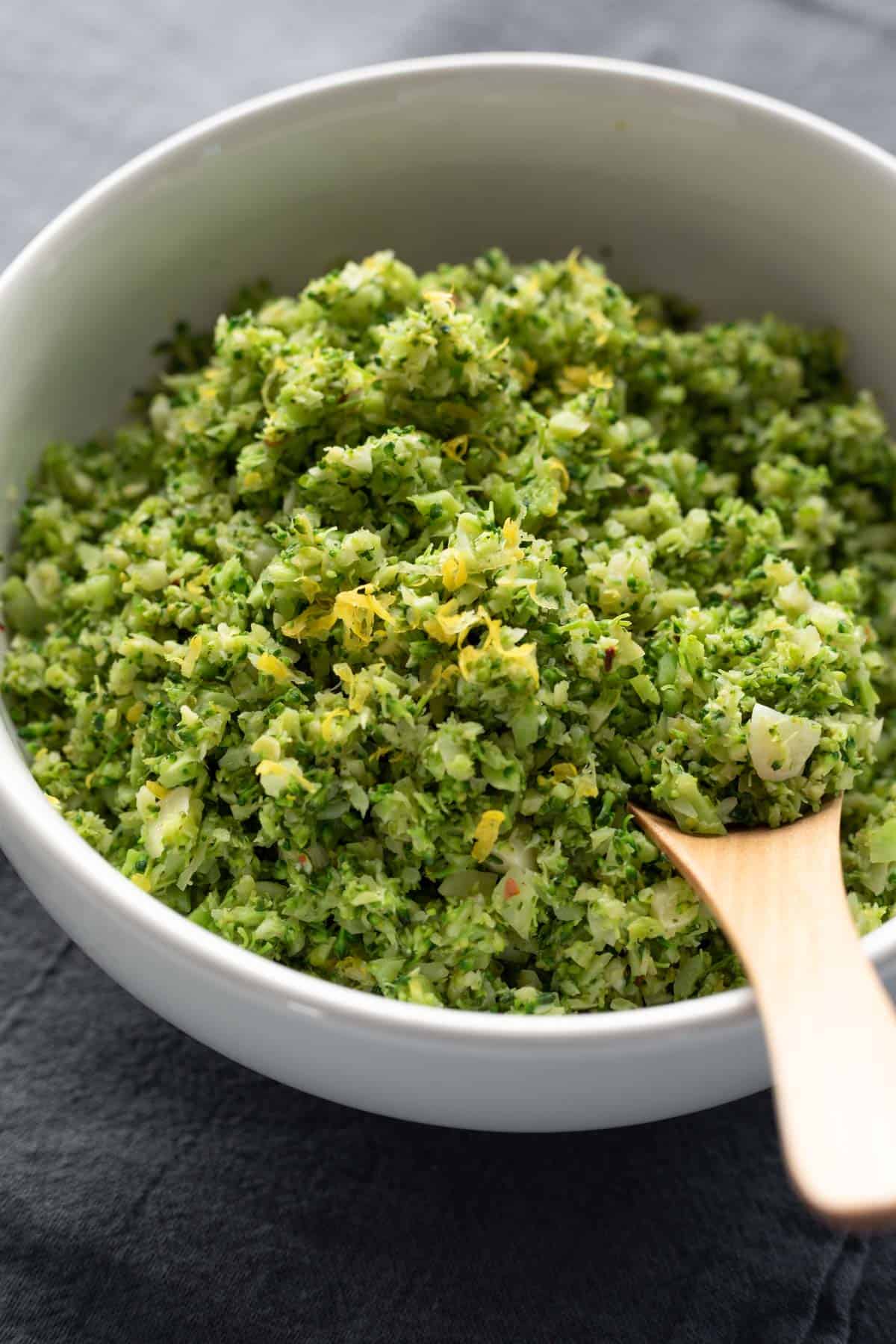 close up of a bowl full of seasoned broccoli rice topped with lemon zest.